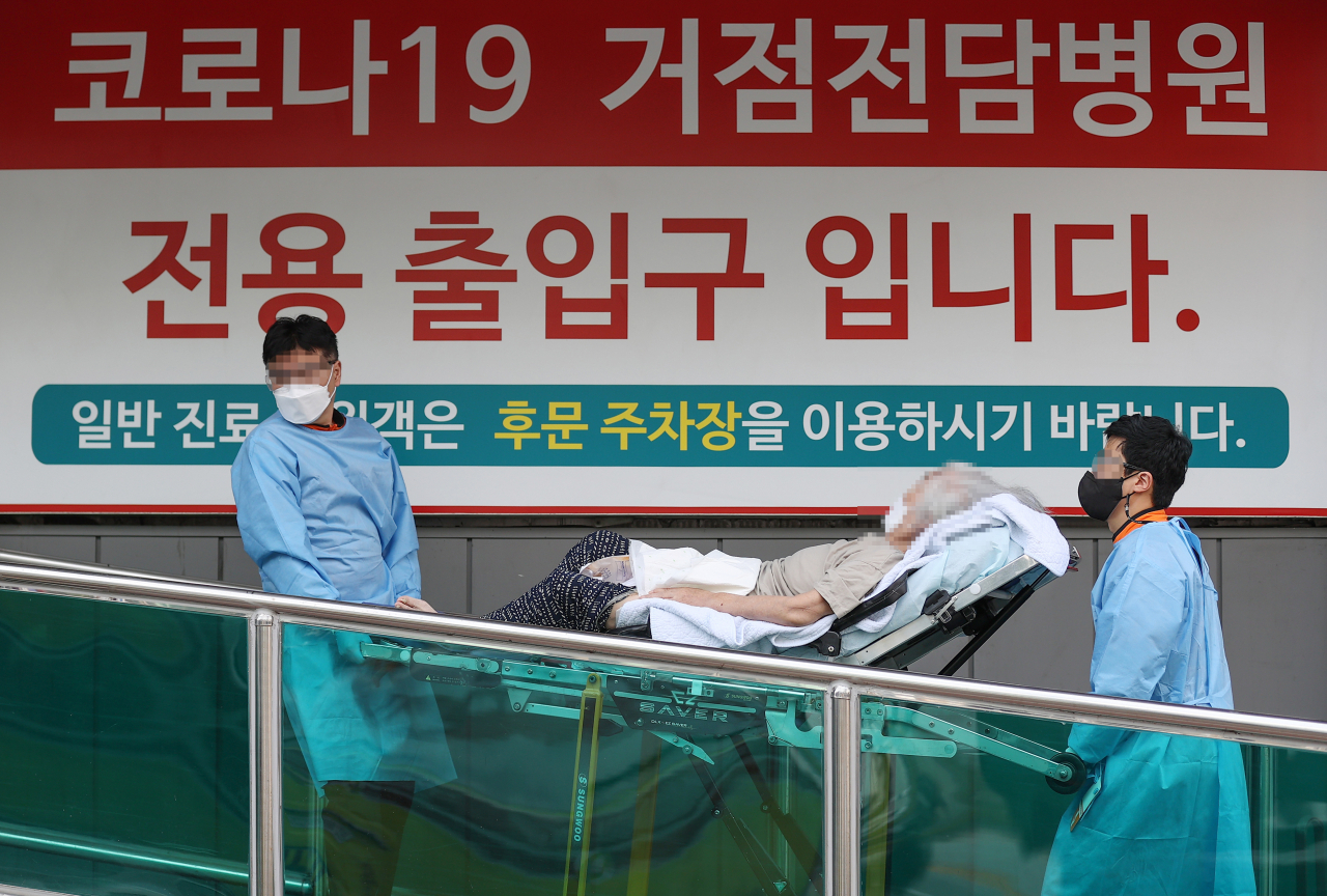 코로나19 위중증 환자 수가 54일만의 최다치(168명)를 기록한 26일 오후 서울 광진구 혜민병원에서 구급대원들이 코로나19 환자를 옮기고 있다. [연합]