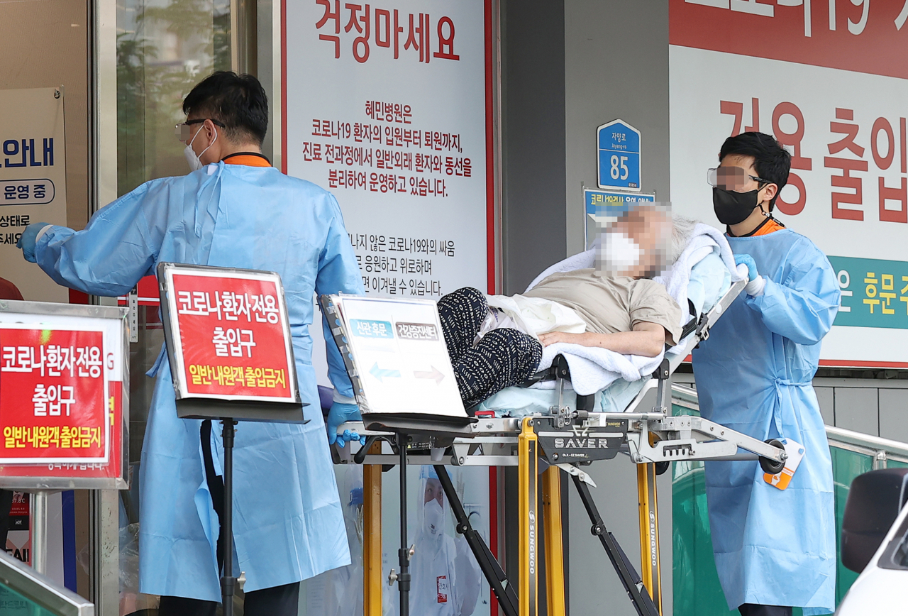 코로나19 위중증 환자 수가 54일만의 최다치(168명)를 기록한 26일 오후 서울 광진구 혜민병원에서 구급대원들이 코로나19 환자를 옮기고 있다. [연합]