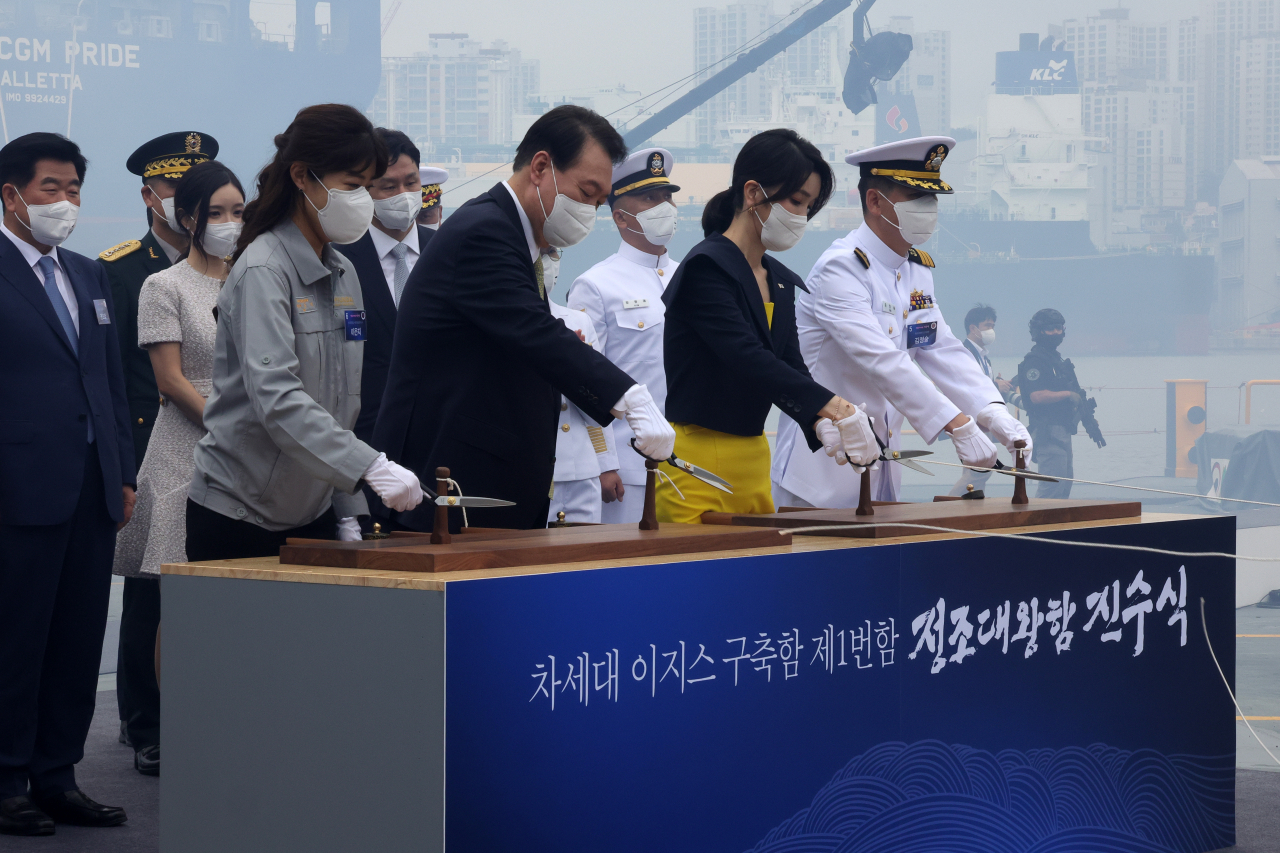 윤석열 대통령과 김건희 여사가 28일 오전 울산시 현대중공업에서 열린 차세대 이지스구축함 정조대왕함 진수식에서 안전항해를 기원하며 샴페인에 연결된 줄을 자르고 있다. [연합]