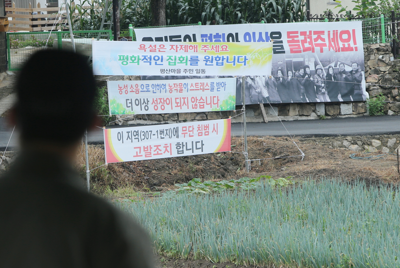14일 낮 경남 양산시 하북면 지산리 평산마을 문재인 전 대통령 사저 앞에 '우리들의 평화와 일상을 돌려주세요' '욕설은 자제해주세요. 평화적인 집회를 원합니다' 등이 적힌 현수막이 걸려 있는 가운데 경호처 직원이 사저 경비를 서고 있다. [연합]
