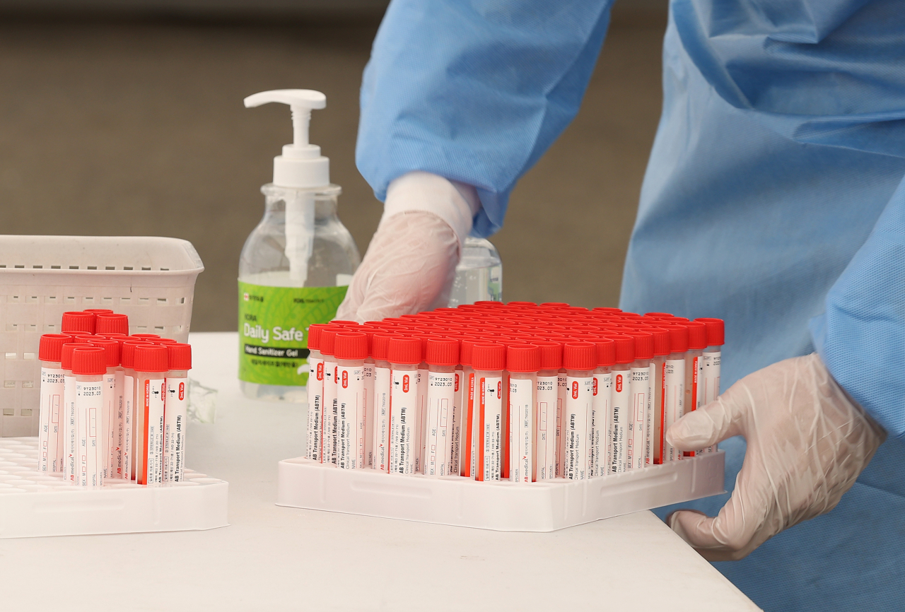 A medical worker handles COVID-19 swab samples at a testing booth near Seoul Station in Seoul on Thursday. (Yonhap)