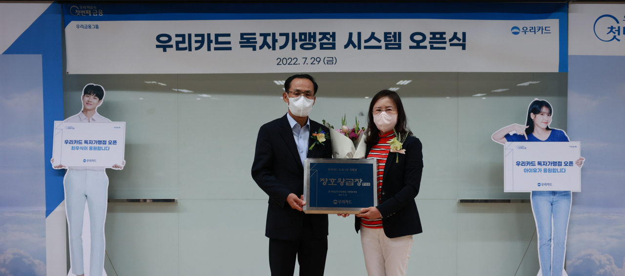우리카드는 29일 우리카드 광화문 본사에서 가맹점 식별 시스템 구축 기념 행사를 가졌다. 김정기 우리카드 사장(왼쪽)과 가맹점 가입 1호 장호왕곱창 종로점주가 기념촬영을 하고 있다.[우리카드 제공]