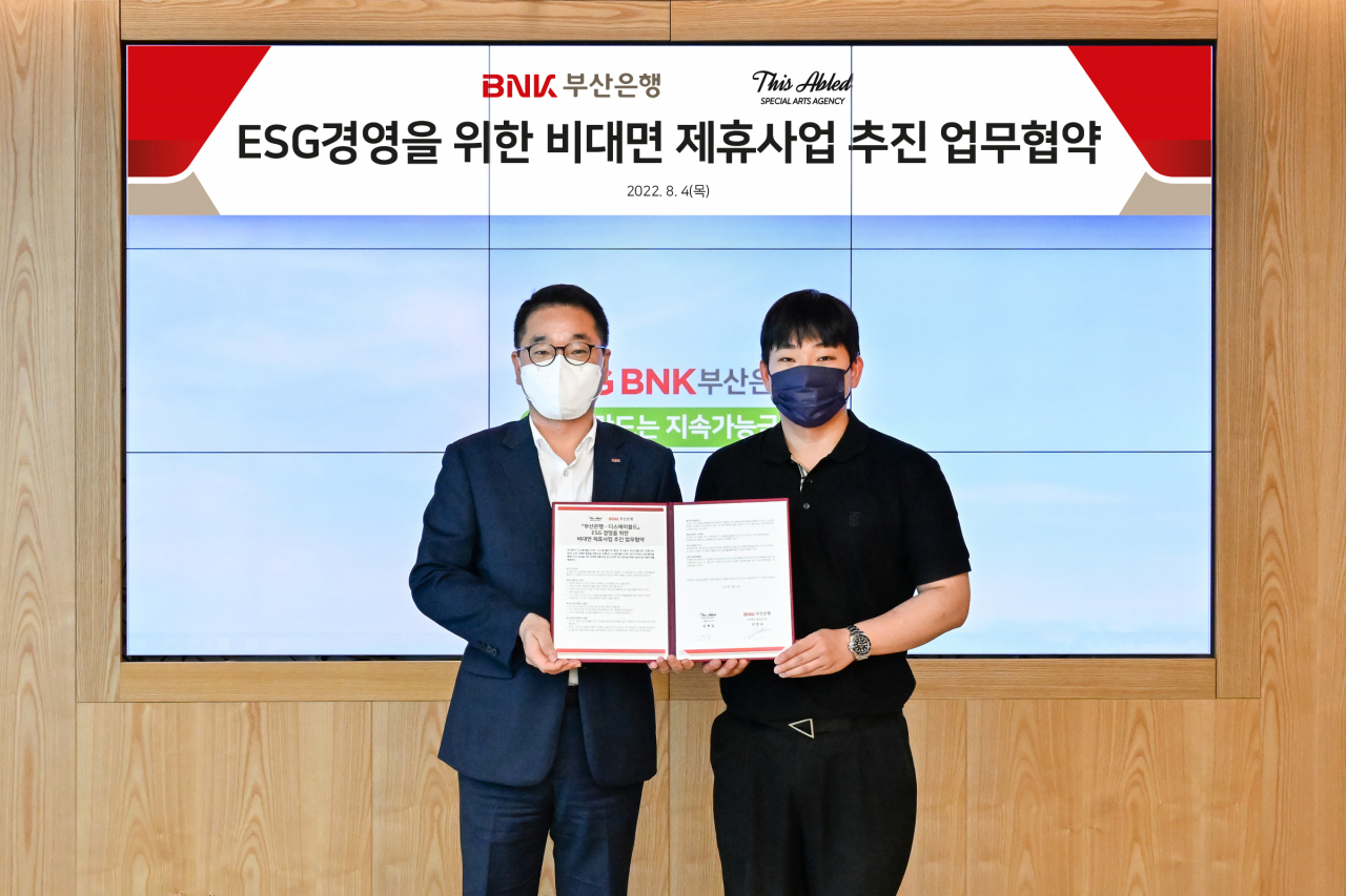 BNK부산은행은 4일 오전, 본점에서 발달장애 예술가 전문 에이전시 ‘디스에이블드(THISABLED)’와 ‘ESG경영을 위한 업무협약’을 체결했다.(사진 왼쪽부터 BNK부산은행 김양욱 언택트영업부장, 디스에이블드 김현일 대표) [부산은행 제공]