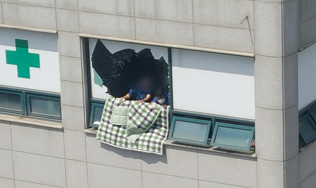 5일 경기도 이천시 관고동 병원 건물에서 화재가 발생, 내부에 있던 병원 관계자들이 환자 대피를 위해 소방대원을 기다리고 있다. [연합]