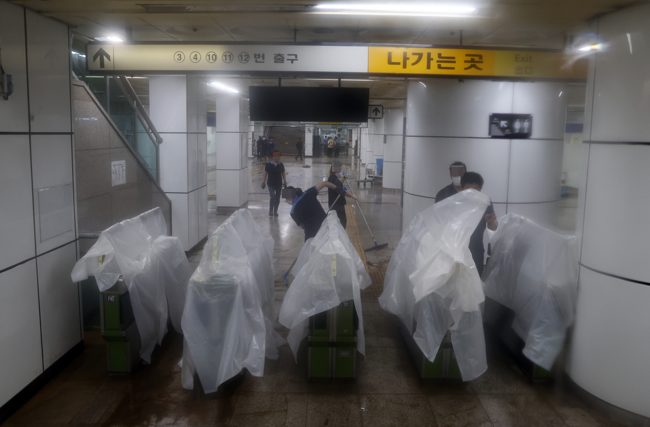 8일 밤 폭우로 침수된 지하철역에서 관계자들이 청소하고 있다. [연합]