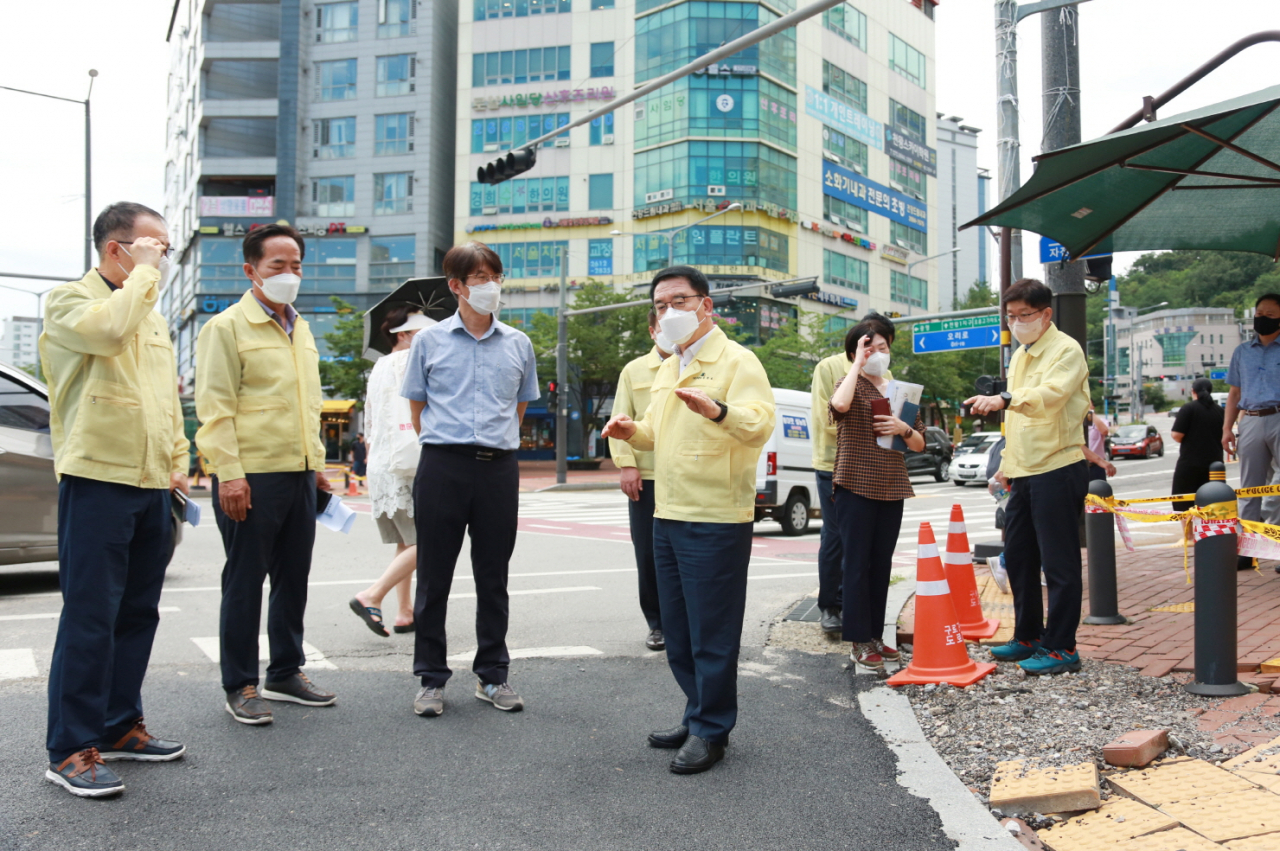 문헌일(왼쪽에서 네번째) 서울 구청장이 천왕역 앞 보도블럭 싱크홀 현장을 찾아 관계자들과 대책을 논의하고 있다. [구로구 제공]