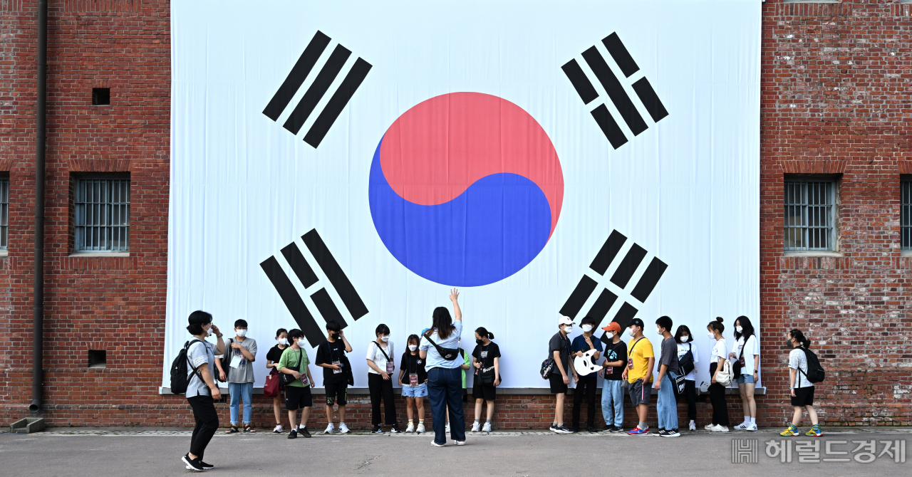제77주년 광복절을 3일 앞둔 12일 서울 서대문구 서대문형무소를 찾은 시립은평청소년센터 돌봄 프로그램 캠프 참가 학생들이 외벽에 걸린 대형 태극기 앞에서 기념사진을 찍고 있다. 임세준 기자