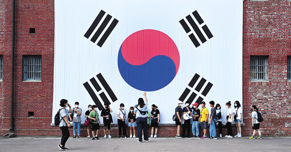 제77주년 광복절을 3일 앞둔 12일 서울 서대문구 서대문형무소를 찾은 시립은평청소년센터 돌봄 프로그램 캠프 참가 학생들이 외벽에 걸린 대형 태극기 앞에서 기념사진을 찍고 있다. 정부는 이날 민생과 경제회복에 중점을 둔 8·15 기업인 특별사면을 단행했다. 임세준 기자