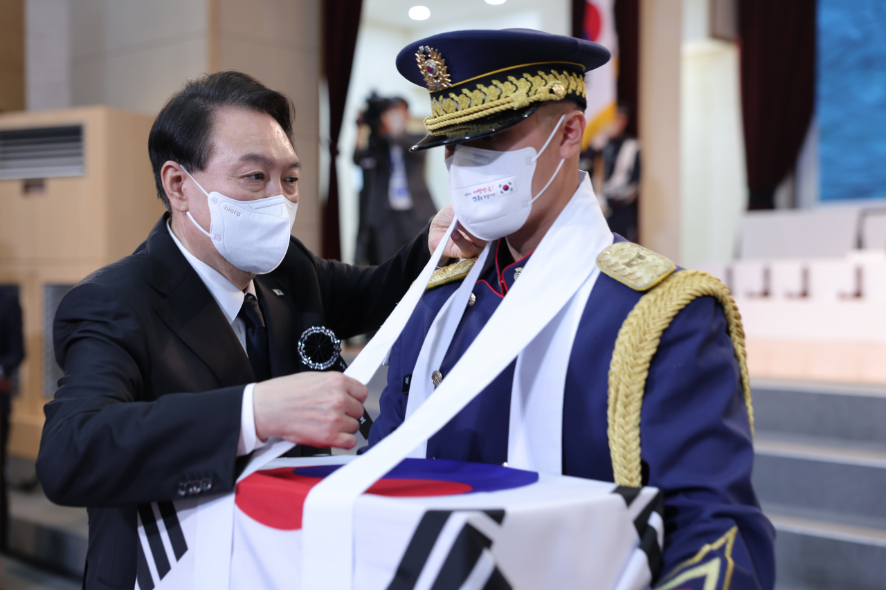 윤석열 대통령이 14일 서울 동작구 국립서울현충원에서 열린 한국광복군 선열 합동 봉송식에서 한 의장대원의 유골함 고정 끈을 바로잡아 주고 있다. [연합]