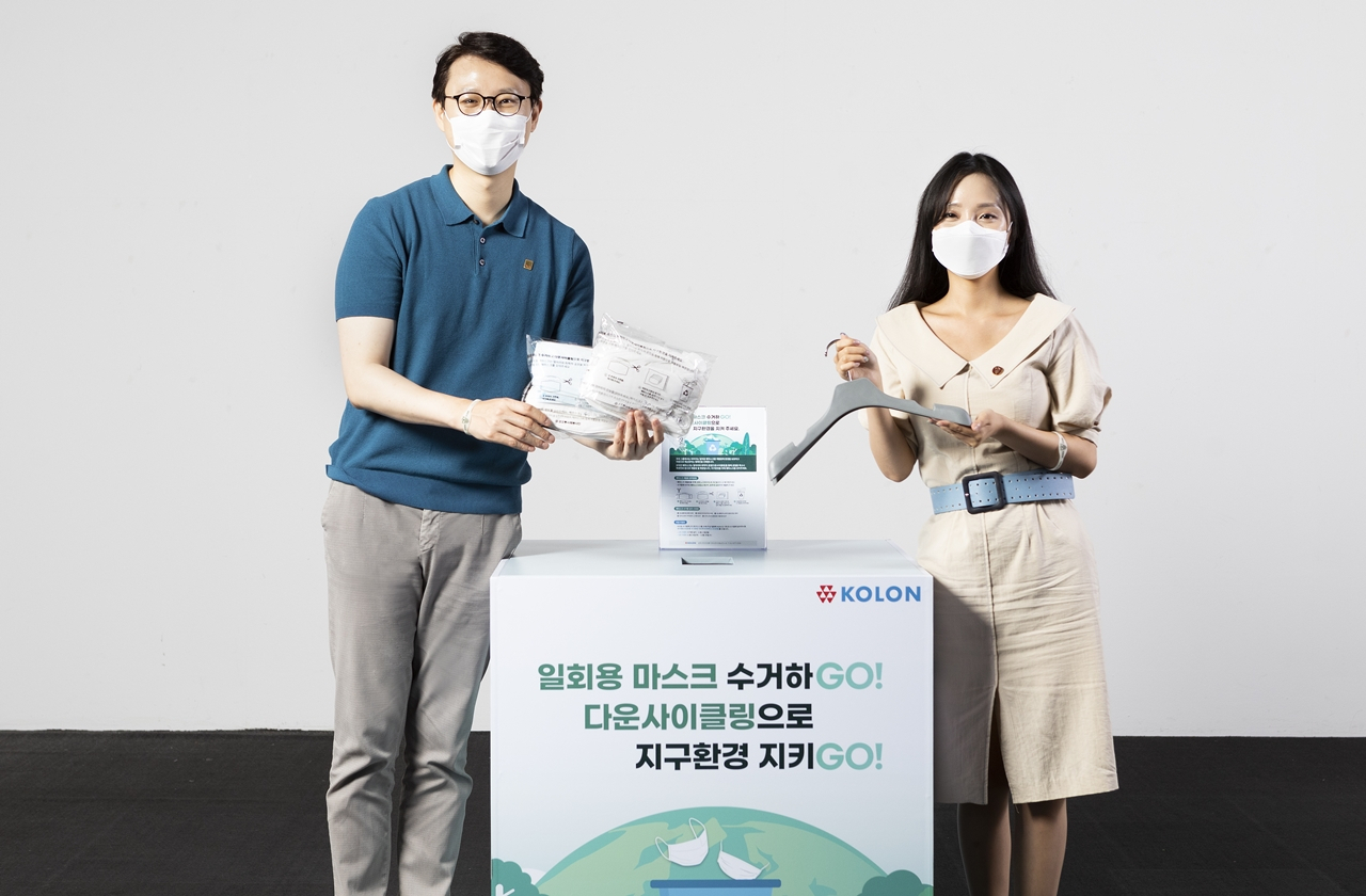 코오롱그룹 임직원들이 사용후 폐마스크를 수거함에 직접 모아 만든 재활용 옷걸이를 마스크 수거함 앞에서 소개하고 있다. [코오롱 제공]
