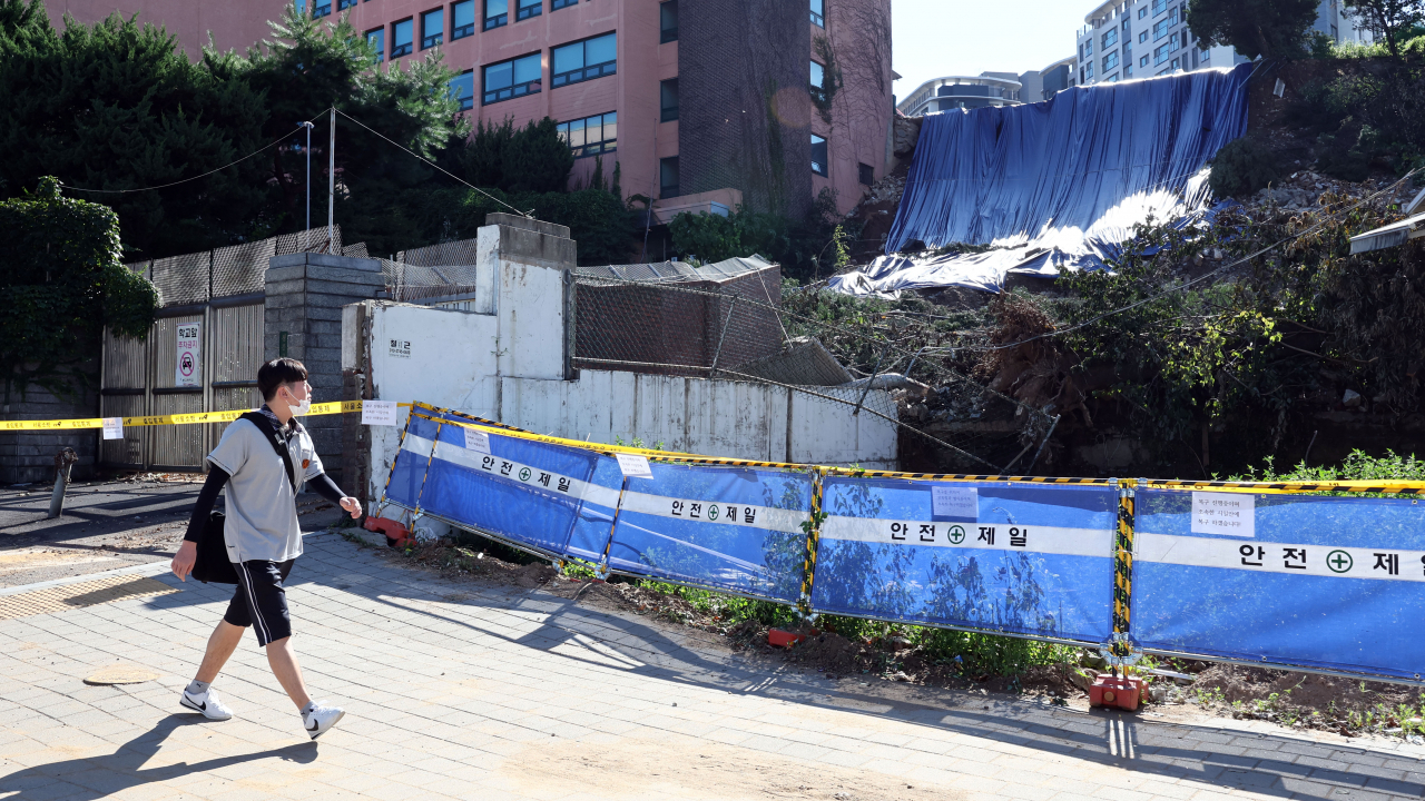 서울 동작구 경문고등학교에서 학생들이 폭우로 인해 산사태가 발생한 후문 앞을 지나가고 있다. [연합]