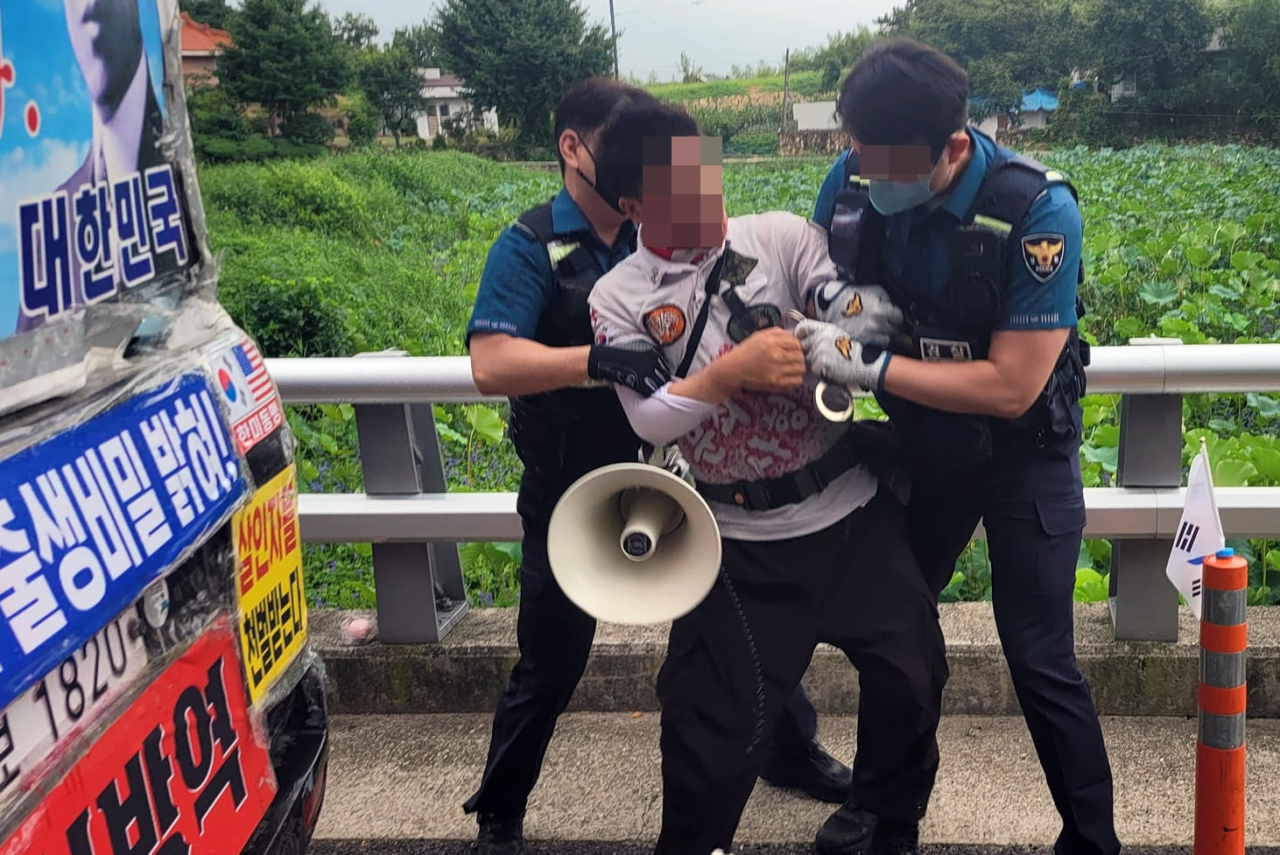 경남 양산경찰서 경찰관들이 지난 16일 문재인 전 대통령 비서실 인사를 커터칼로 협박하는 등 소란을 피운 평산마을 장기 1인 시위자를 특수협박 혐의로 체포하고 있다. [연합뉴스 제공]