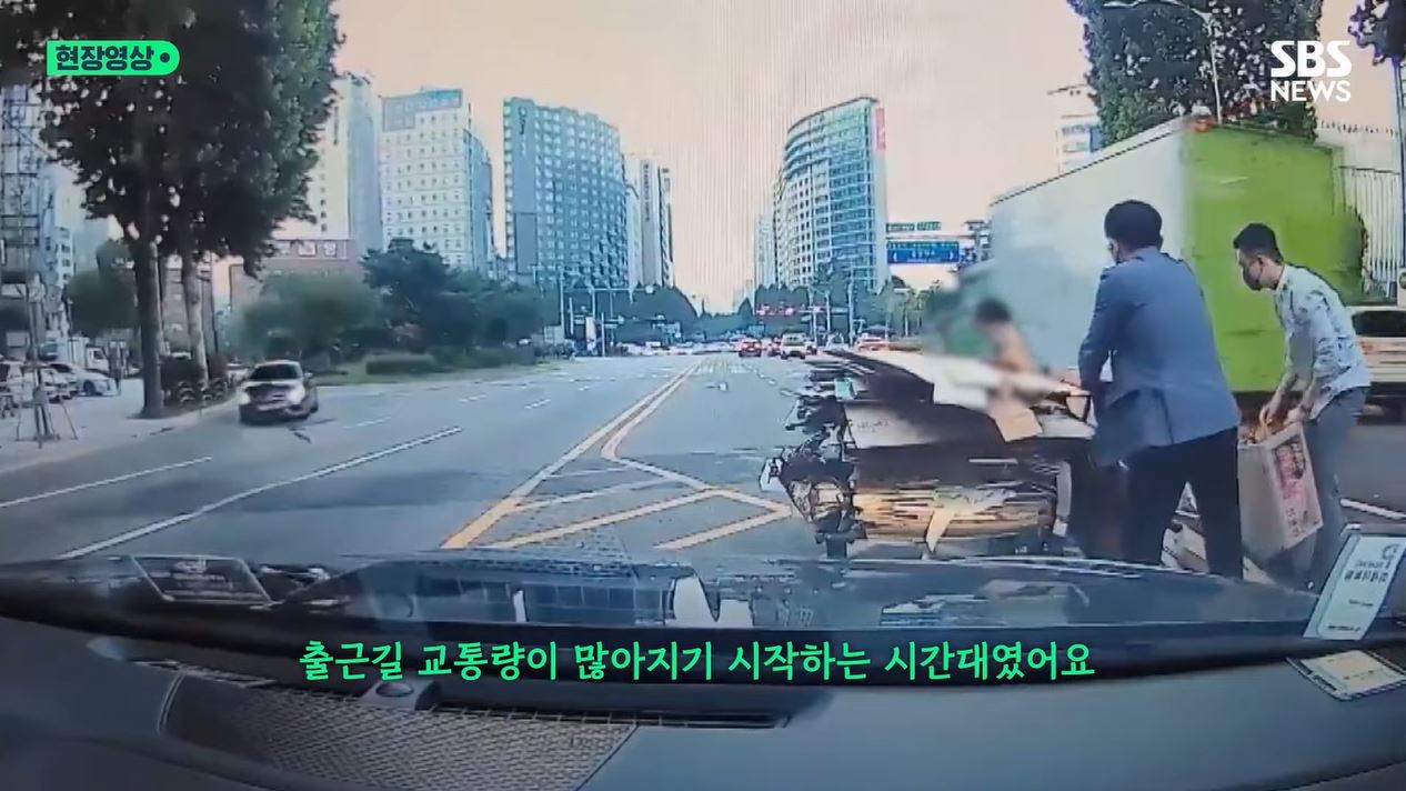 지난 18일 서울 강서구 6차대로에서 한 할머니가 끌던 수레에서 폐지가 쏟아지자 두 남성이 발 벗고 나섰다. [SBS 방송화면]