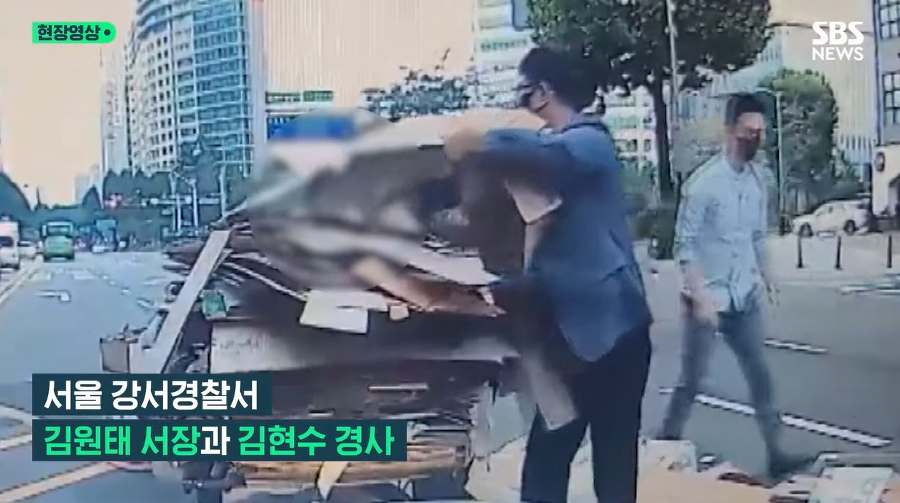 지난 18일 서울 강서구 6차대로에서 한 할머니가 끌던 수레에서 폐지가 쏟아지자 두 남성이 발 벗고 나섰다. [SBS 방송화면]