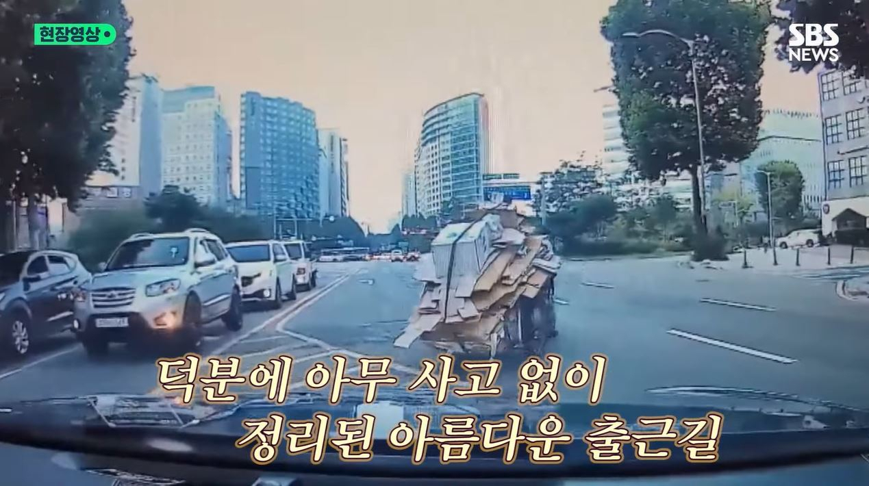 지난 18일 서울 강서구 6차대로에서 한 할머니가 끌던 수레에서 폐지가 쏟아졌다. 이에 차량을 타고 지나가던 서울 강서경찰서 소속 김원태 서장과 김현수 경사가 폐지 수습을 도왔다. [SBS 방송화면]
