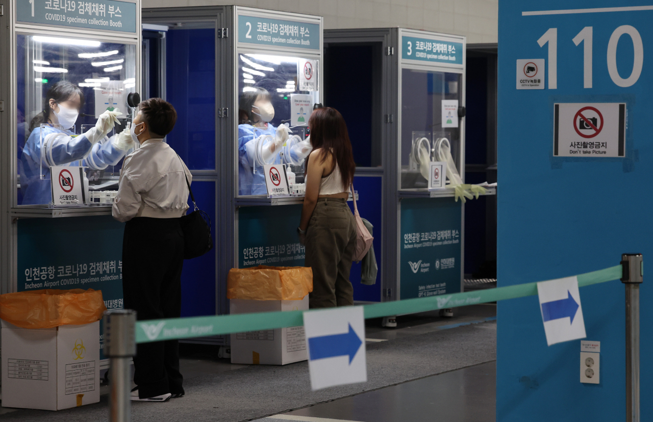 Medical workers take COVID-19 swab samples from foreign travelers at testing booth set up in a main passenger terminal of Incheon International Airport, west of Seoul, on Monday. (Yonhap)