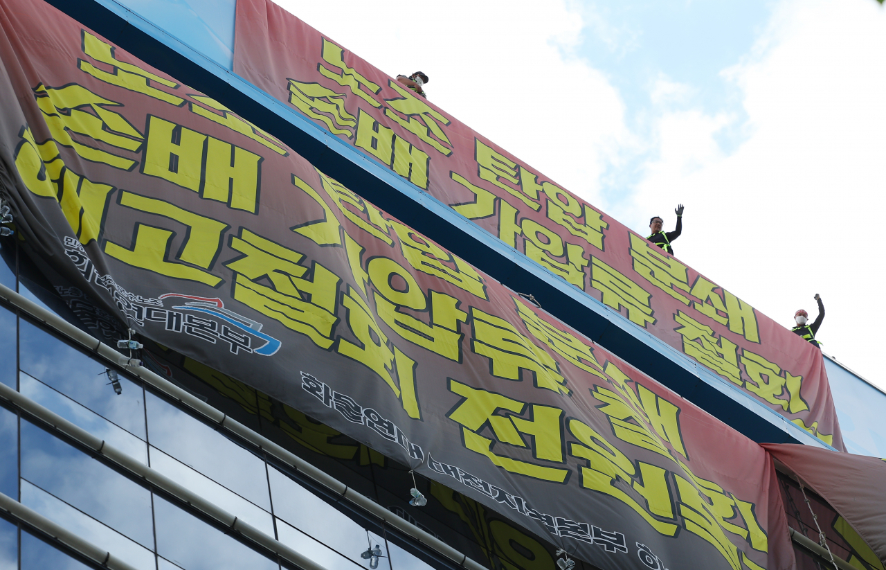 지난 24일 공공운수노조 화물연대 조합원들이 하이트진로 본사 건물 옥상에서 농성을 벌이고 있다. [연합]