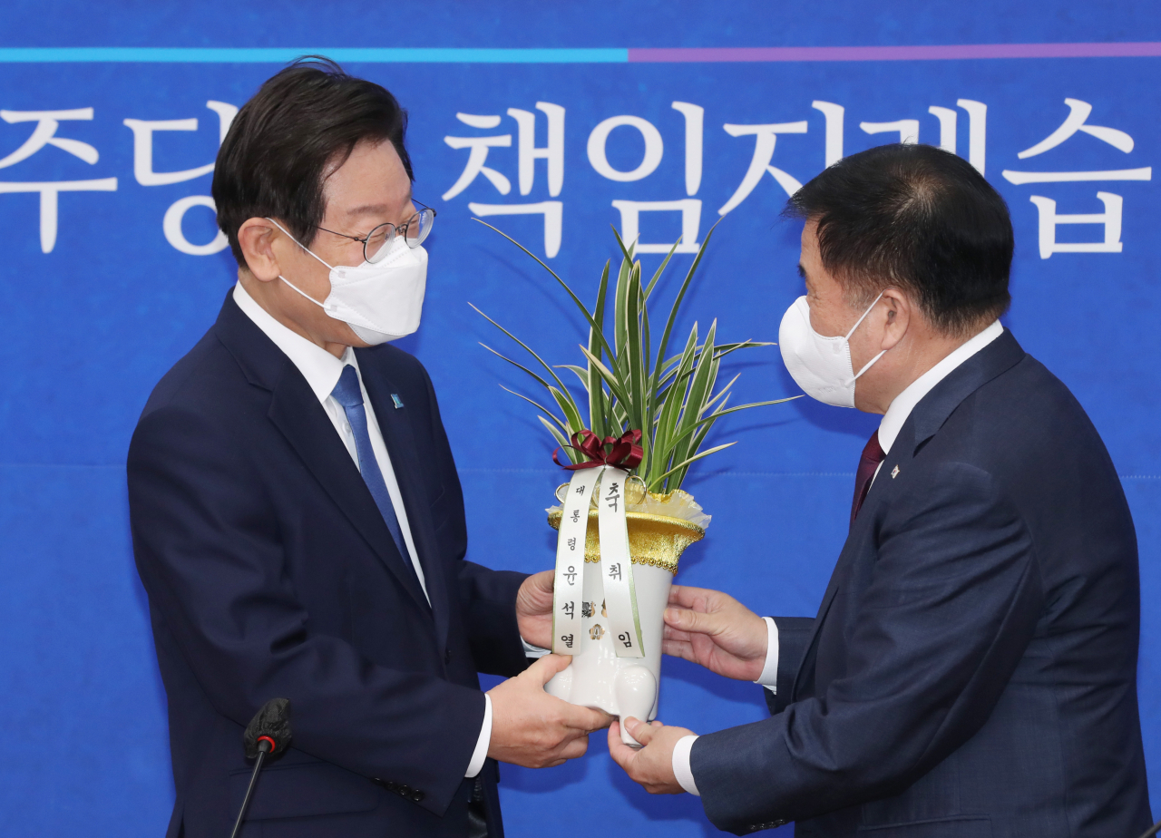 이재명 더불어민주당 신임 당대표가 30일 오전 서울 여의도 국회 대표실을 방문한 이진복 대통령실 정무수석으로부터 축하 난을 받고 있다. 이상섭 기자