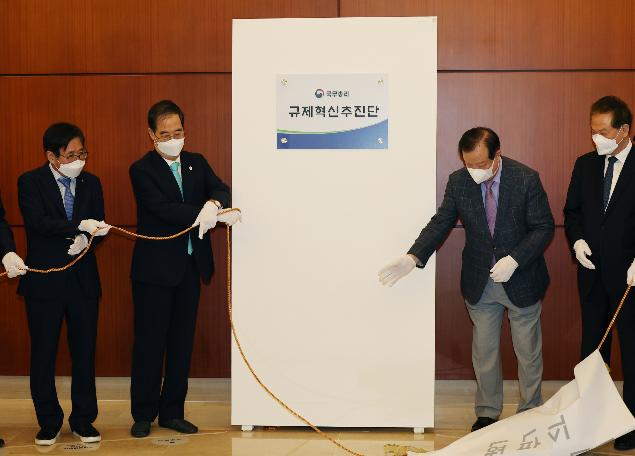 한덕수 국무총리(왼쪽 두 번째)가 31일 서울 종로구 이마빌딩에서 규제혁신 추진단 현판을 제막하고 있다. [연합]