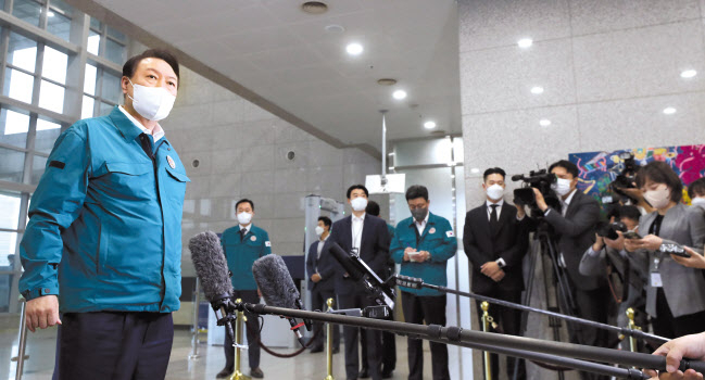 초록색 민방위복을 입은 윤석열 대통령이 5일 오전 서울 용산 대통령실 청사로 출근하며 기자들의 질문에 북상하는 태풍 힌남노 관련 국민안전에 최선을 다하겠다고 밝히고 있다.[연합]