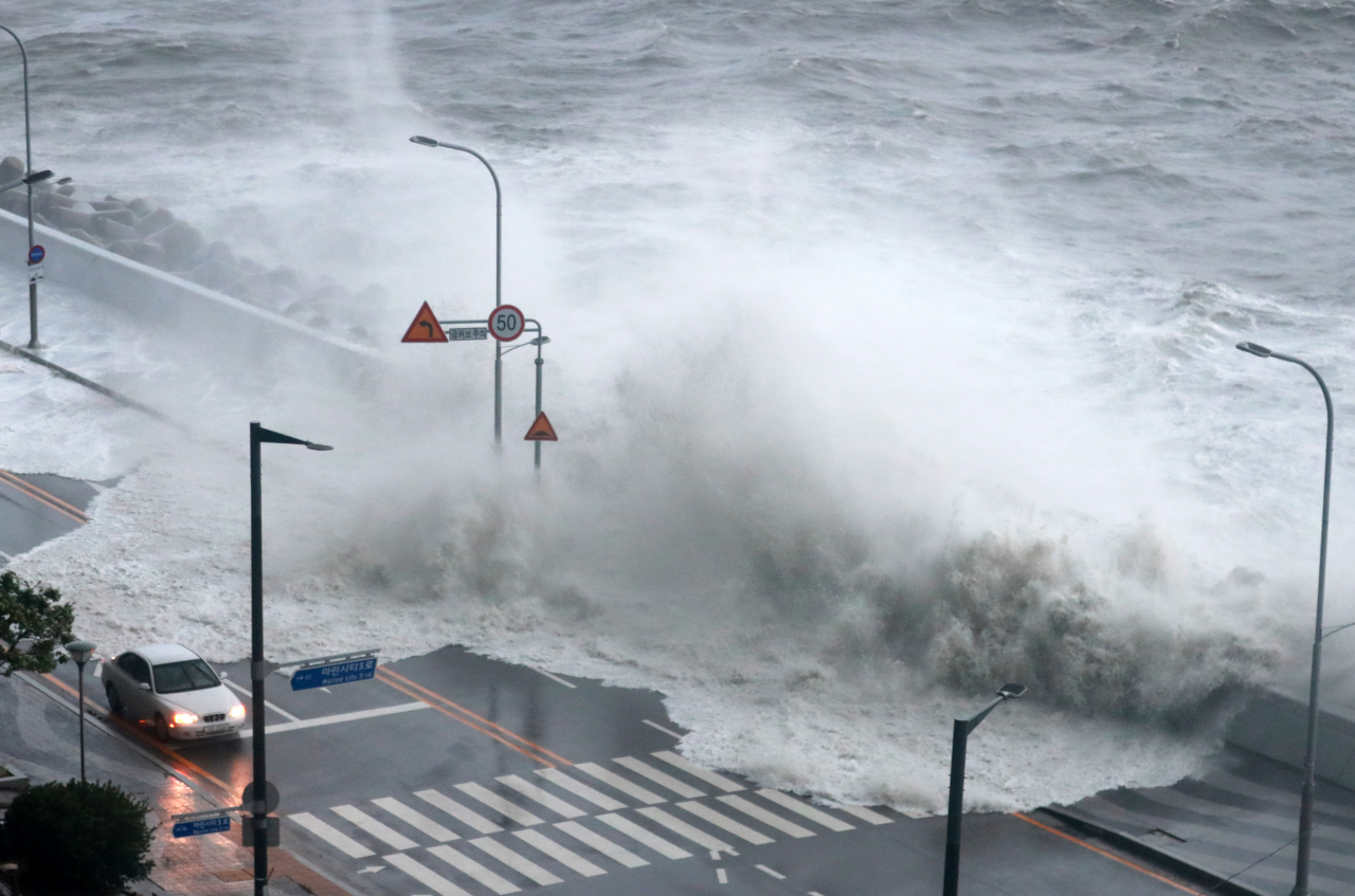 A high tide wave hits a coastal road near Marine City in Busan.