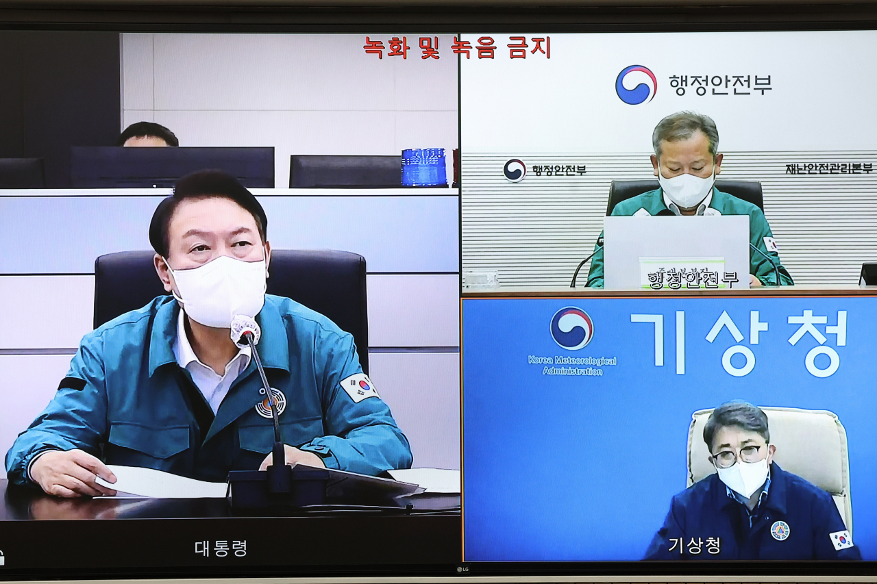 윤석열 대통령이 5일 밤 서울 용산 대통령실 청사 국가위기관리센터에서 제11호 태풍 '힌남노'와 관련 제주 현지 CCTV 영상을 통해 태풍 상륙 상황을 지켜보며 유희동 기상청장으로부터 화상 보고를 받고 있다. [연합]