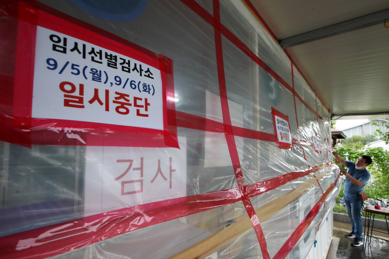 태풍 힌남노가 북상 중인 5일 광주 서구 5·18민주화운동교육관에 마련된 코로나19 임시선별검사소에서 의료진이 태풍에 대비한 안전조치를 한 뒤 일시중단 안내문을 붙이고 있다. [연합]