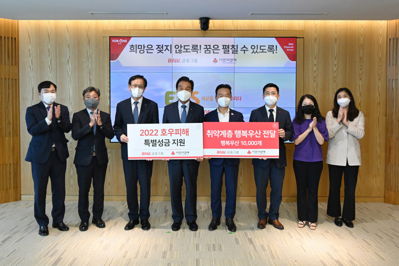 BNK금융그룹은 6일 본사에서 호우 피해에 대한 복구 지원과 예방을 위해 부산사회복지공동모금회에 특별성금 1억원과 행복우산 1만개를 전달했다. 사진 왼쪽 세 번째부터 구교성 BNK금융지주 그룹경영지원부문장, 김지완 BNK금융그룹 회장, 부산사회복지공동모금회 최금식 회장, 박은덕 사무처장.[BNK금융그룹 제공]