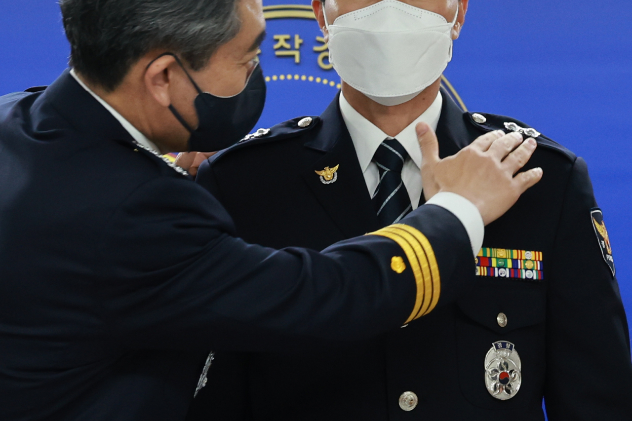윤희근 경찰청장(왼쪽)이 7일 오후 서울 동작경찰서에서 범인 검거자 특진 임용식에 참석해 태국인 마약류 유통 조직을 검거한 박성원 경위의 정복에 경감 계급장을 달아준 뒤 매무새를 만져주고 있다. [연합]