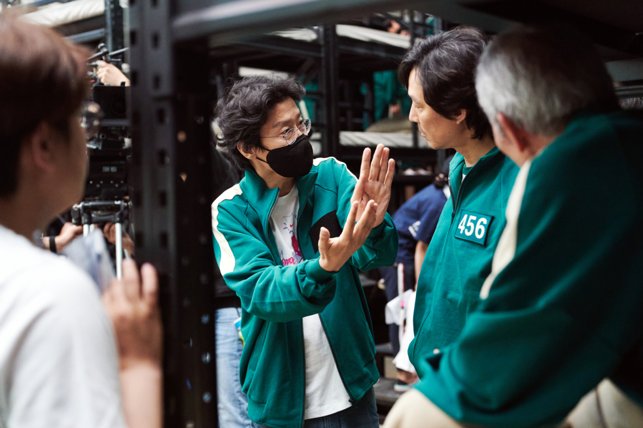 "Squid Game" director Hwang Dong-hyuk (center) speaks with Lee Jung-jae (right). (Netflix)