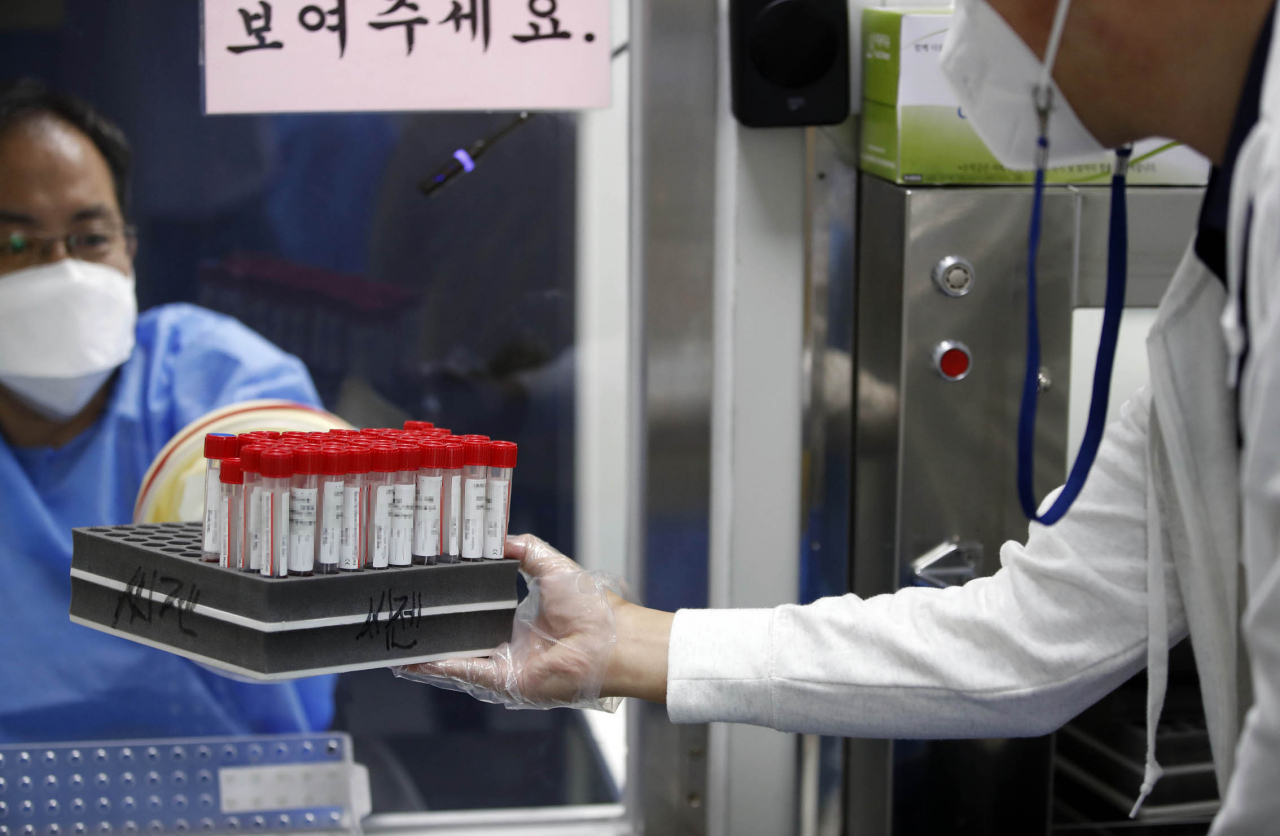 추석 연휴가 끝난 13일 광주 북구 선별진료소에서 보건소 의료진이 검체통을 운반하고 있다. [연합]