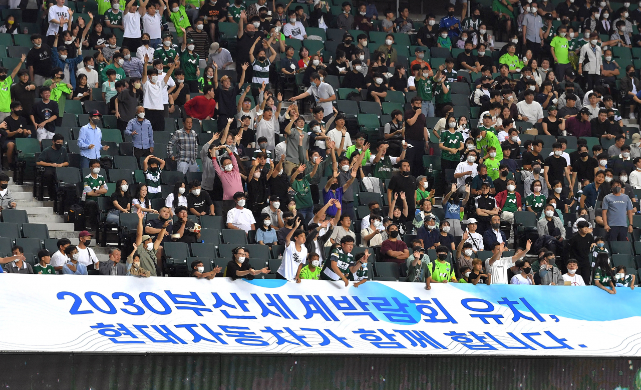 전북 현대 모터스의 홈구장인 전주월드컵 경기장에서 열린 FC서울과의 경기 중 부산세계박람회 유치를 응원하는 대형 플래카드가 설치된 관중석에서 축구팬들이 환호하고 있다. [현대차그룹 제공]