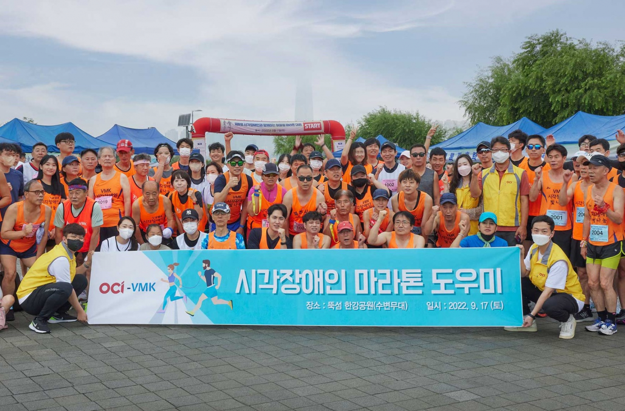 지난 17일 서울 뚝섬한강공원에서 열린 ‘시각장애인과 함께하는 어울림 마라톤대회’에 동반주자로 함께 뛴 OCI 신입사원 등이 기념촬영을 하고 있다. [OCI 제공]