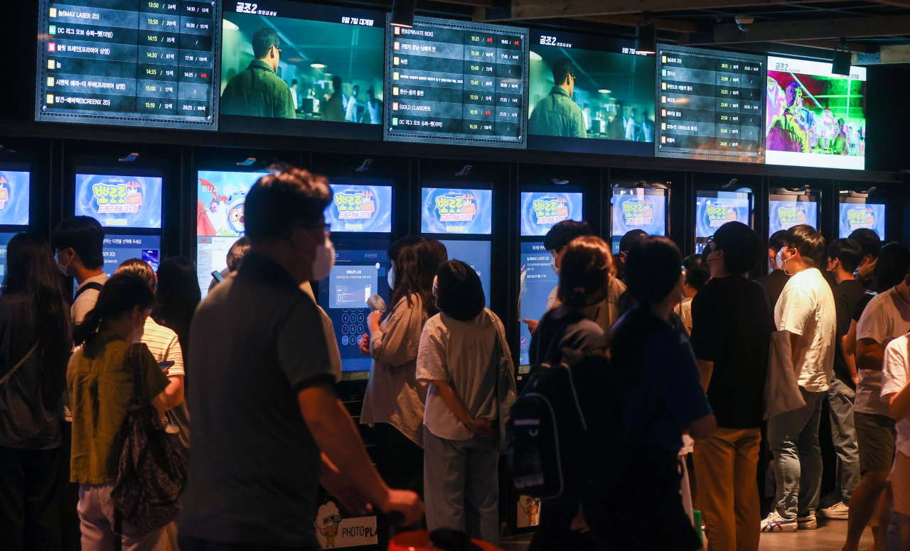 Moviegoers wait to buy tickets from kiosks at a cinema in downtown Seoul. (Yonhap)