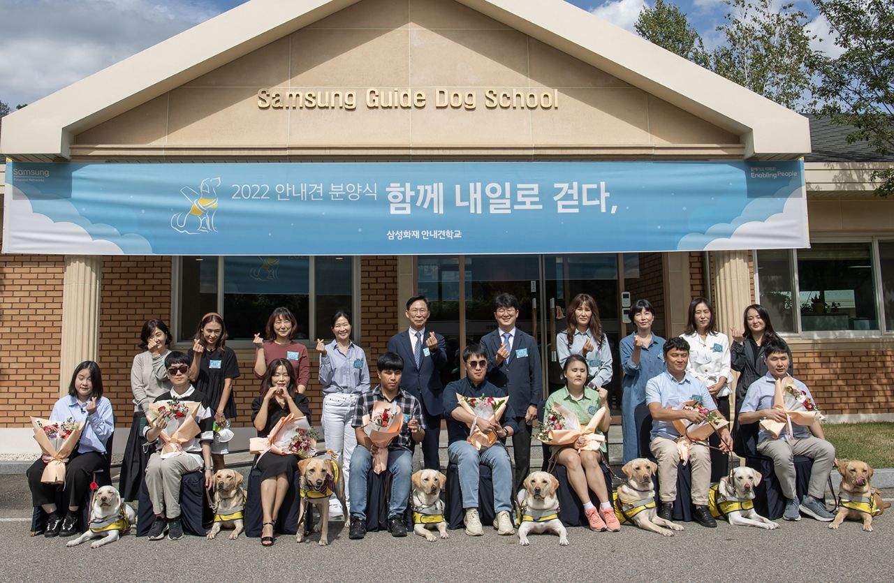 20일 용인 삼성화재안내견학교에서 시각장애인 파트너와 이들과 함께 새롭게 안내견 활동을 시작하는 안내견, 퍼피워커(자원봉사자), 삼성화재안내견학교 관계자들이 기념 촬영을 하고 있다.[삼성 제공]