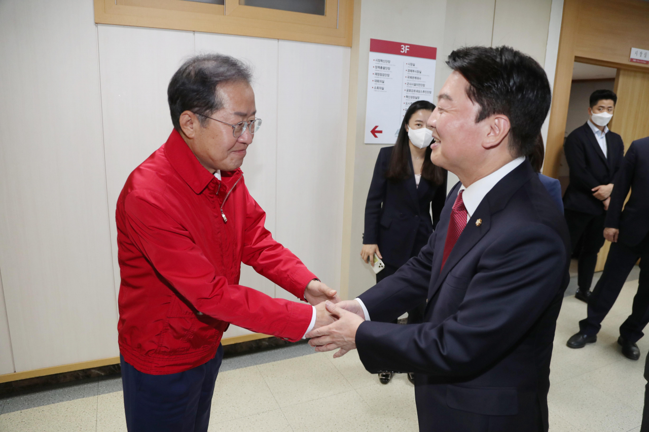 홍준표 대구시장과 국민의힘 안철수 의원이 21일 대구시청 산격청사에 만나 악수하고 있다. [연합]
