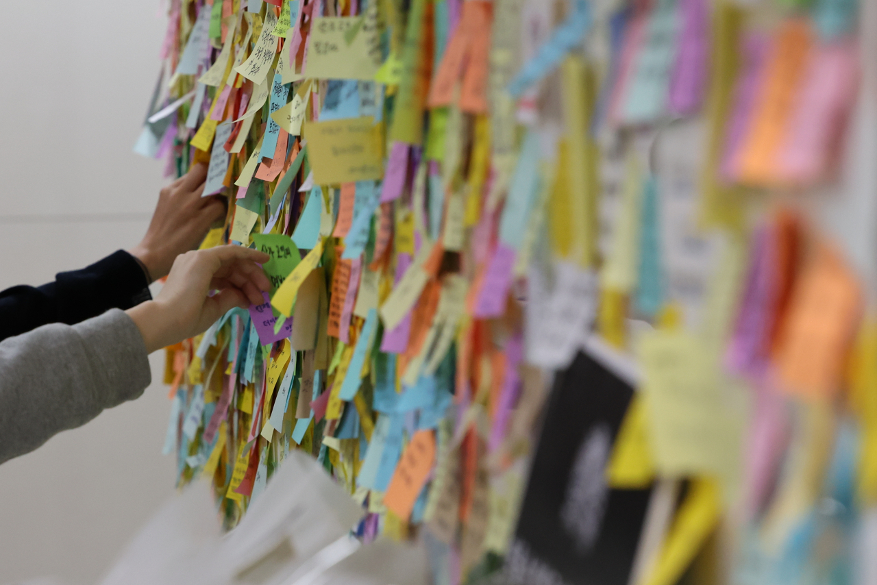 A passerby leaves messages of condolences Tuesday at Sindang station, Seoul, mourning for victim who had been murdered at the station last Wednesday. After the murder, in which a woman was killed by her stalker a day before the court was to decide a case against him on charges of stalking, critics pointed out that the killing could have been prevented if he had been held in custody. (Yonhap)