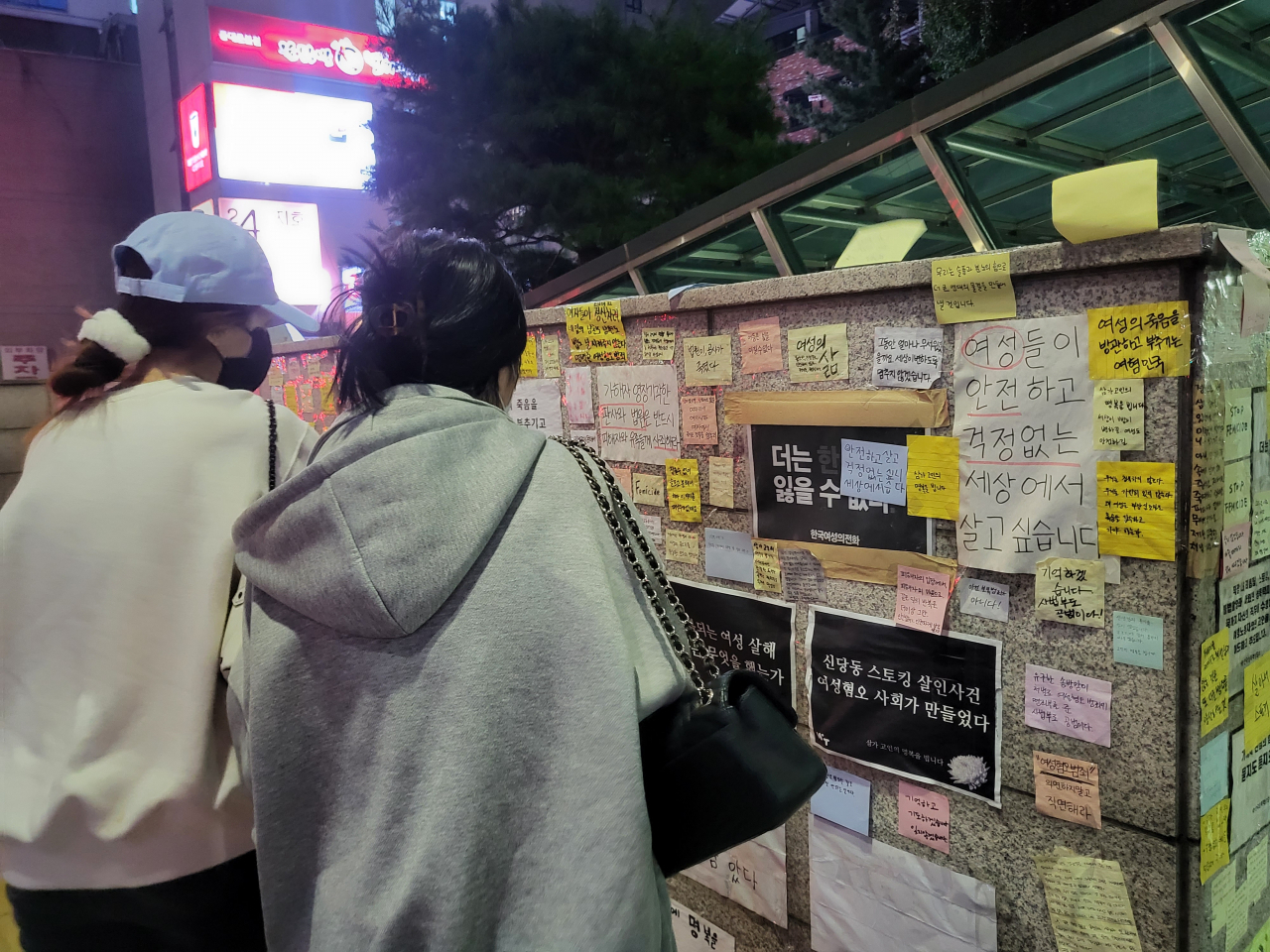 시민들이 지난 28일 오후 7시께 서울 중구 신당역 10번 출구 앞에 마련된 추모 공간에 붙은 포스트잇 추모 메시지들을 들여다보고 있다. 박혜원 기자