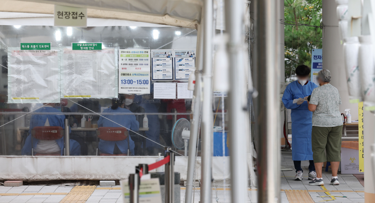 A medical worker talks to a visitor at a COVID-19 testing station in a community health center in Seoul's western district of Mapo last Wednesday. (Yonhap)