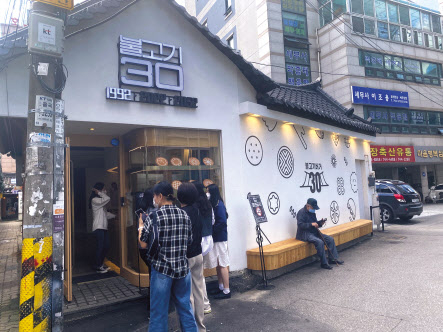 지난 5일 정오 서울시 종로구 익선동 롯데리아 플래그십스토어 불고기랩에서 방문객이 사진을 찍고 있는 모습(위쪽)과 인근의 롯데리아 플래그십스토어 불고기랩 앞에 방문객들이 줄을 서고 있다. 신주희 기자