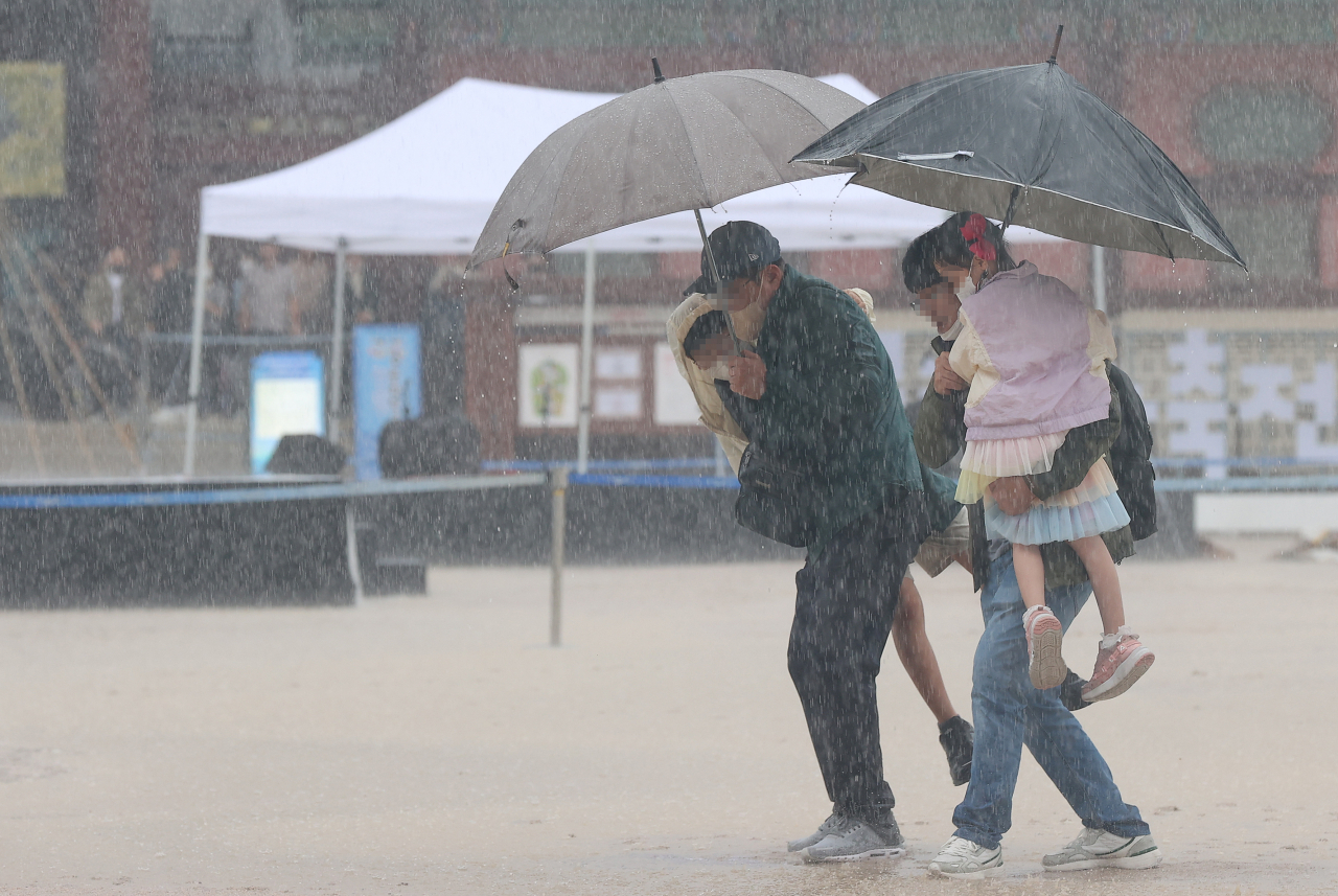지난 3일 오전 서울 종로구 경복궁을 찾은 시민들이 우산을 쓰고 이동하고 있다. [연합]