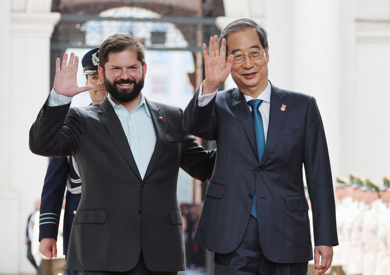 한덕수 국무총리가 11일(현지시간) 칠레 산티아고 대통령궁에서 열린 공식환영식에 참석해 가브리엘 보리치 대통령과 손을 들어 인사하고 있다. [연합]