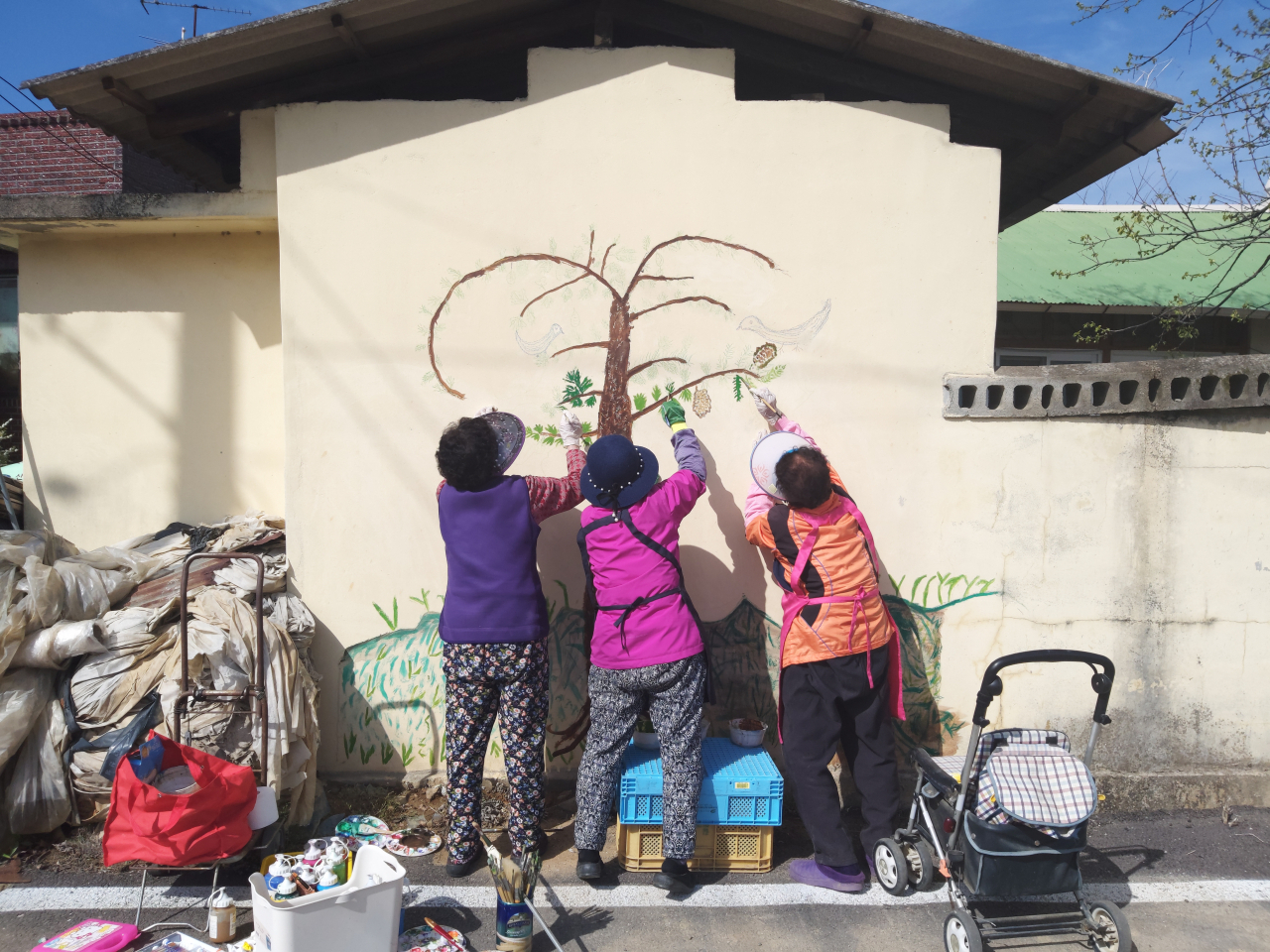Women paint a wall at a village in Sinpung-ri, Yecheon, North Gyeongsang Province, in 2021. (Sinpung Art Museum)