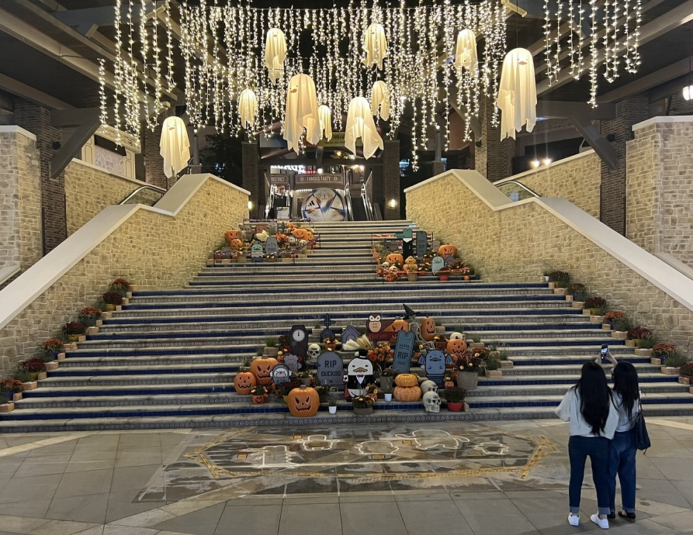 부산 신세계 프리미엄 아울렛 스페인 계단에 조성된 할로윈 콘셉트로 조성된 포토존을 배경으로 고객들이 사진 촬영을 하고 있다.[신세게사이먼 제공]