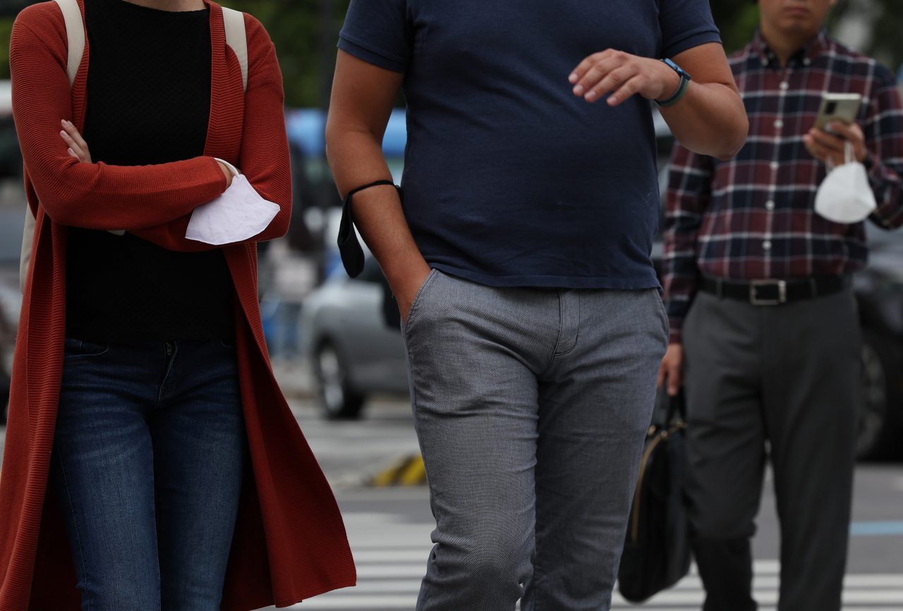People hold masks on a street in Seoul on Sept. 26, as the government lifted the outdoor mask mandate. (Yonhap)
