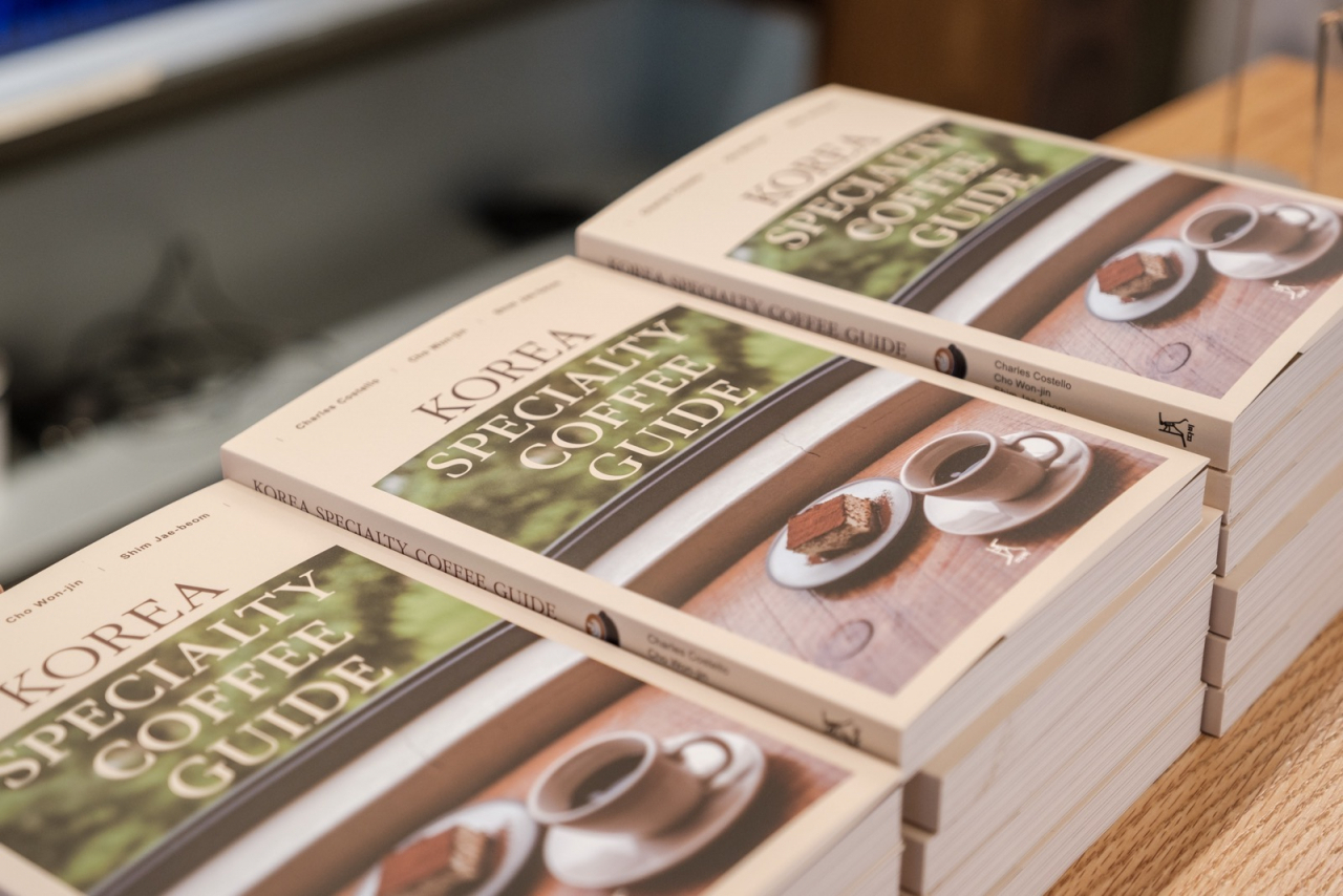 “Korea Specialty Coffee Guide” books by Charles Costello, Cho Won-jin and Shim Jae-beom are stacked on a table. (Courtesy of Cho Won-jin)