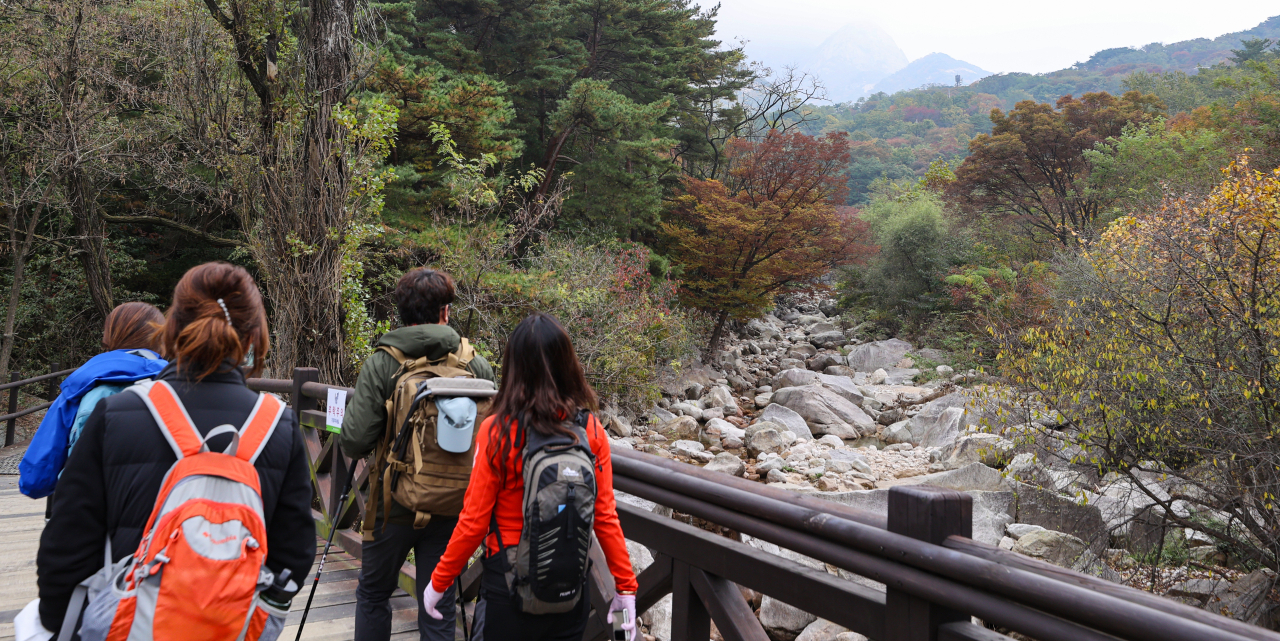 23일 오전 등산객들이 서울 은평구 북한산에서 단풍으로 물든 산을 바라보고 있다. [연합]