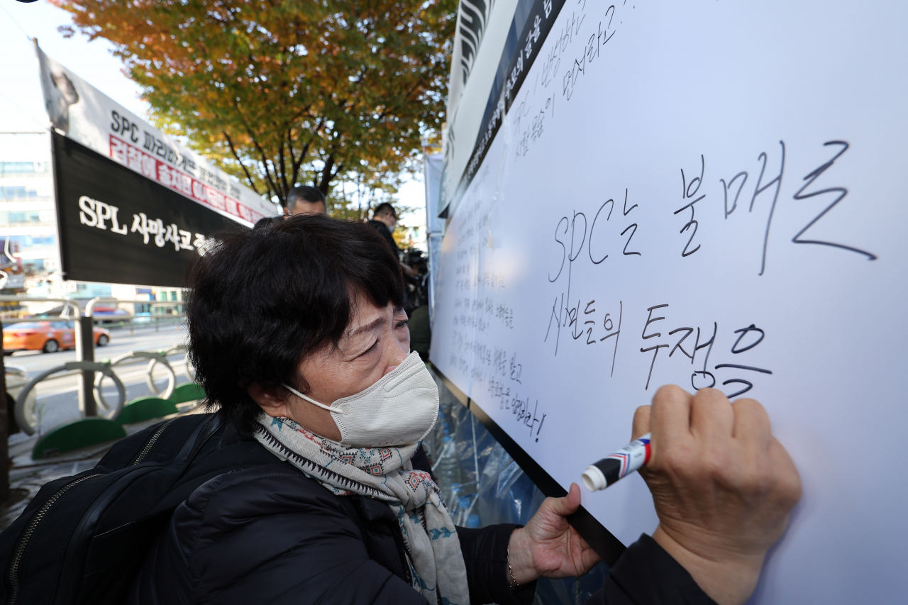 지난 20일 오후 서울 서초구 SPC그룹 본사 앞에서 열린 평택 SPC 계열사 SPL의 제빵공장 사망 사고 희생자 서울 추모행사에서 한 시민이 추모의 글을 남기고 있다. [연합]