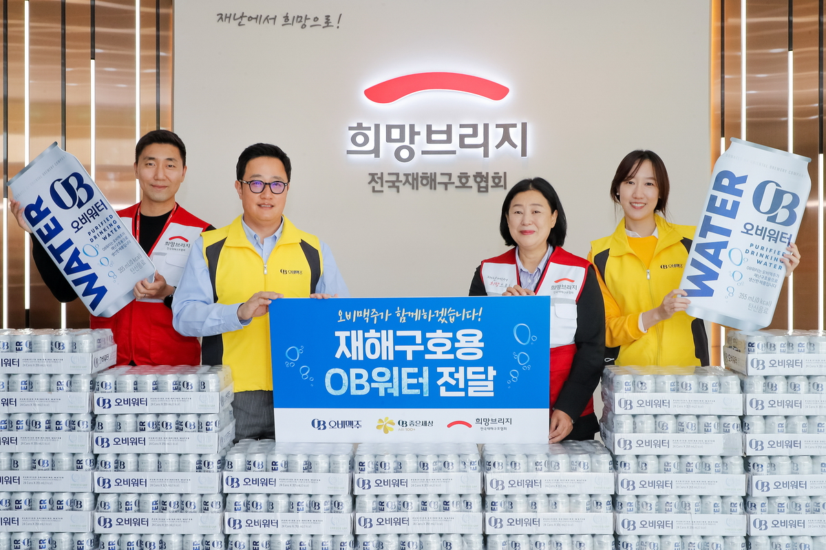 오비맥주 법무정책홍보부문 구자범 부사장(왼쪽 두번째)과 희망브리지 전국재해구호협회 김정희 사무총장(오른쪽 두번째)이 희망브리지 파주재해구호물류센터에서 OB워터 기증행사를 열고 기념촬영을 하고 있다. [오비맥주 제공]]