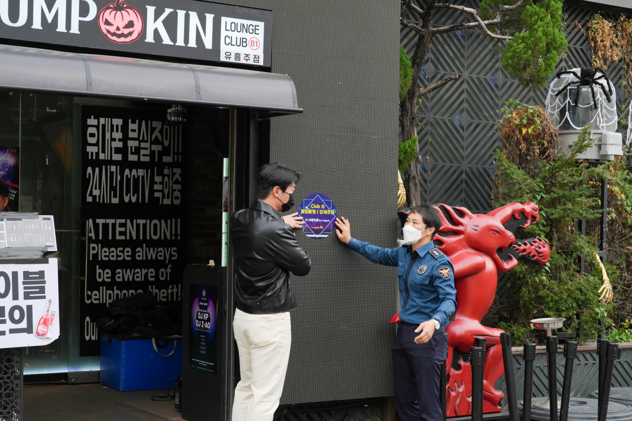 서울 용산구 이태원거리 상인과 서울 용산경찰서 관계자가 오는 31일 핼러윈데이에 대비해 불법촬영 및 강제추행 범죄를 예방하는 포스터를 부착하고 있다. [용산경찰서 제공]
